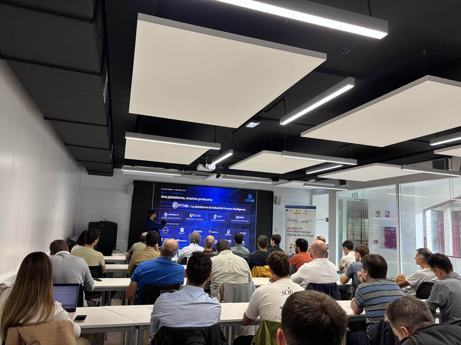 Sala del IMH Campus de Elgoibar llena de asistentes durante la ponencia de Diego Tuccillo, con la diapositiva de la plataforma PYTH-IA de Deduce Data Solutions en pantalla