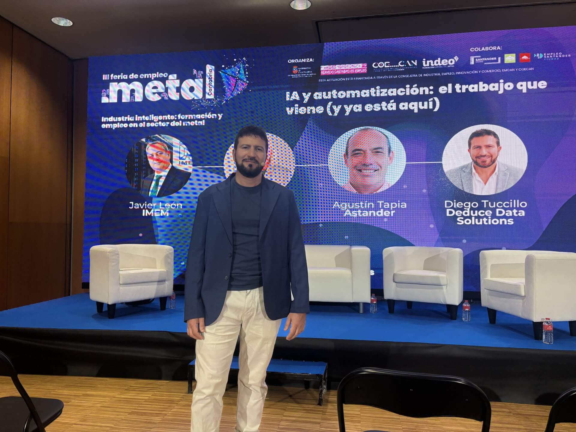 Escenario de la Feria de Empleo del Metal de Cantabria antes de la mesa redonda IA y automatización, con los ponentes en la pantalla